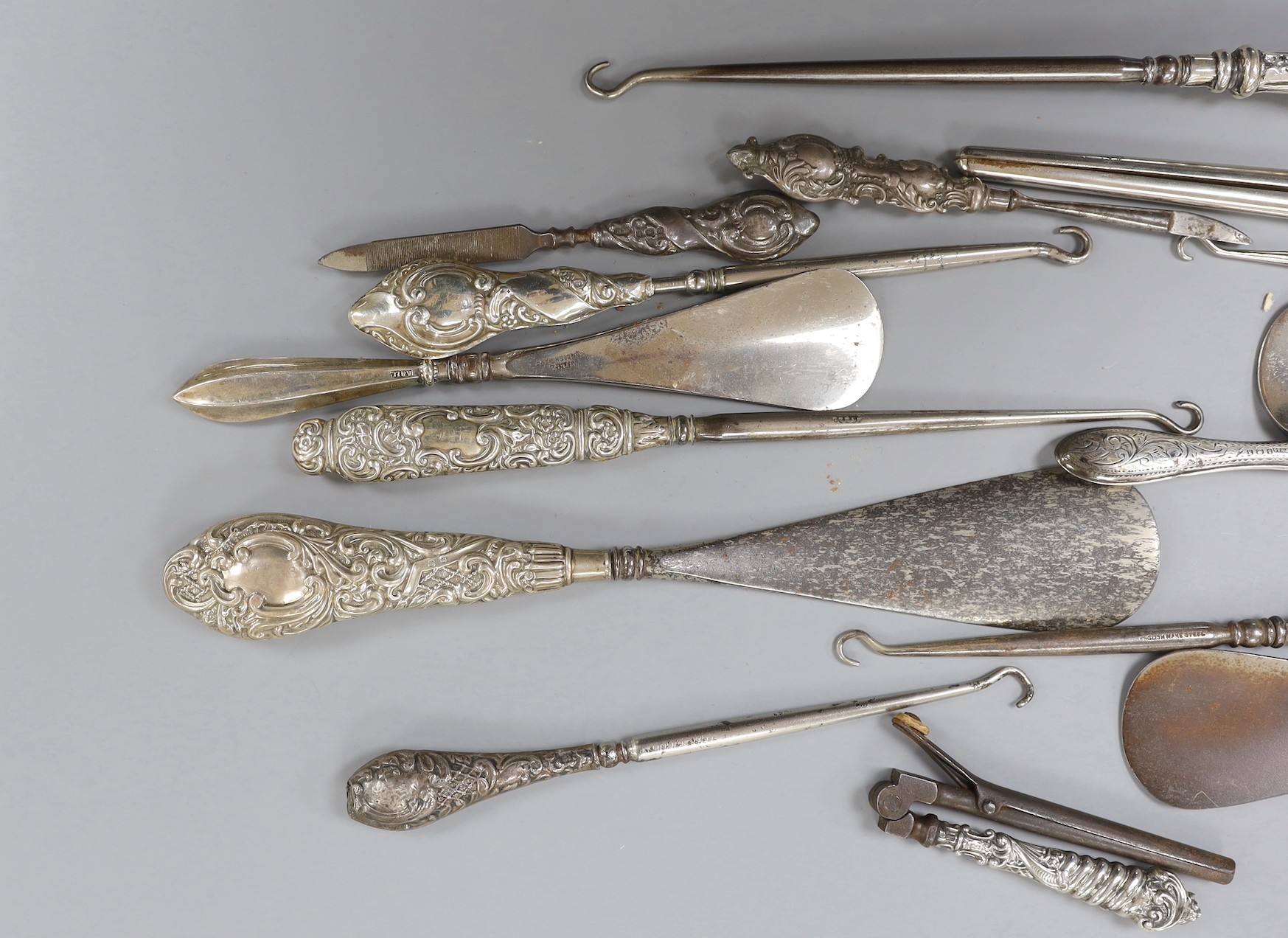Four repousse silver handled shoe horns, seven similar button hooks, three nail implements, a pair glove stretchers and small pair of curling tongs.
